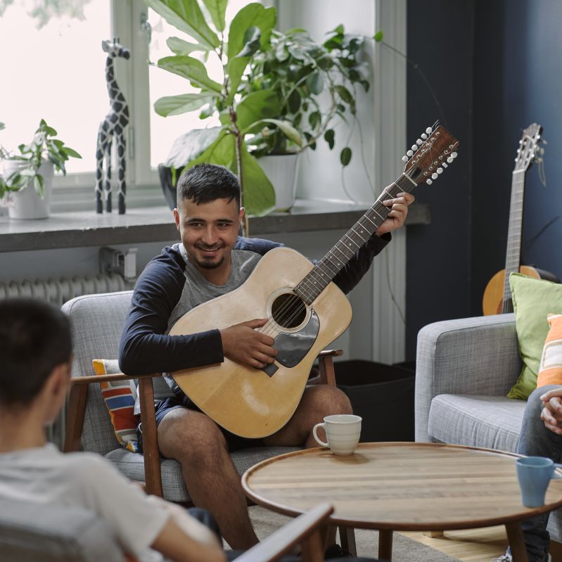 man sitter och spelar gitarr