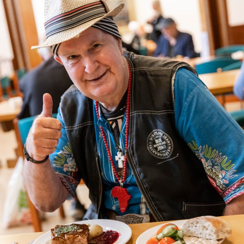 Man gör tummen upp medan han äter på en av Stockholms Stadsmissions mötesplatser.