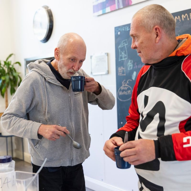 Två män pratar över en kopp kaffe på vår dagverksamhet för män i hemlöshet.