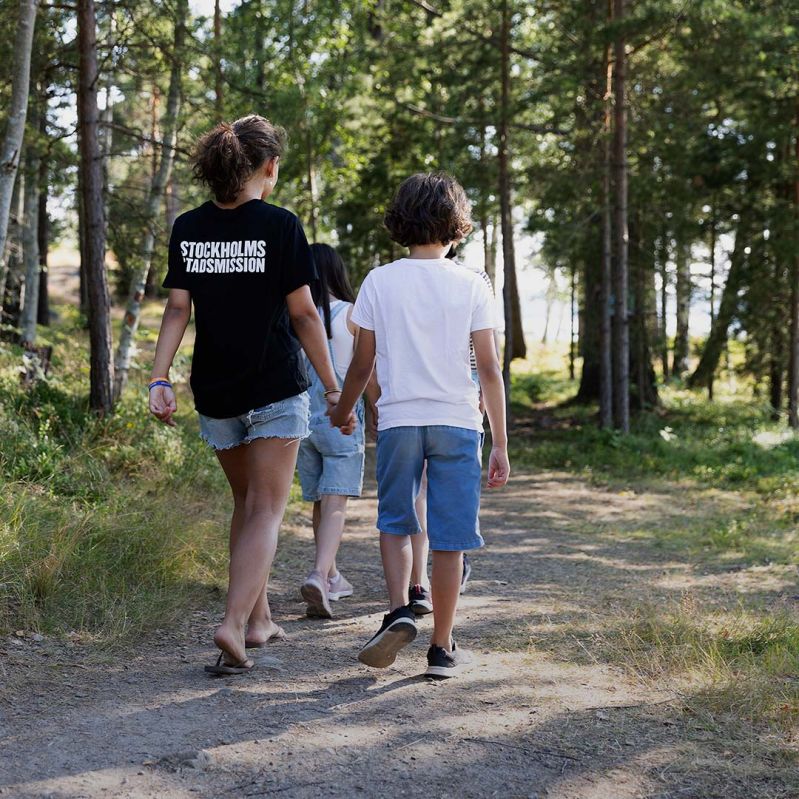 Tre barn går längs en stig på sommarkollo.