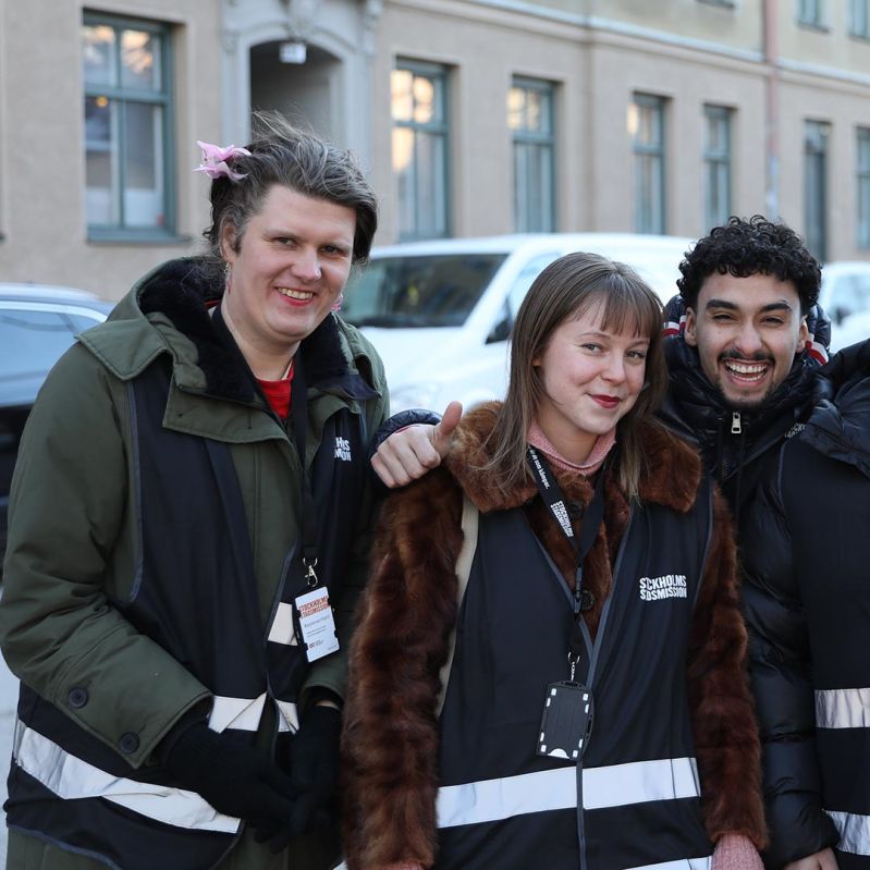 Tre värvare från Stockholms Stadsmission i svarta västar med ränder.