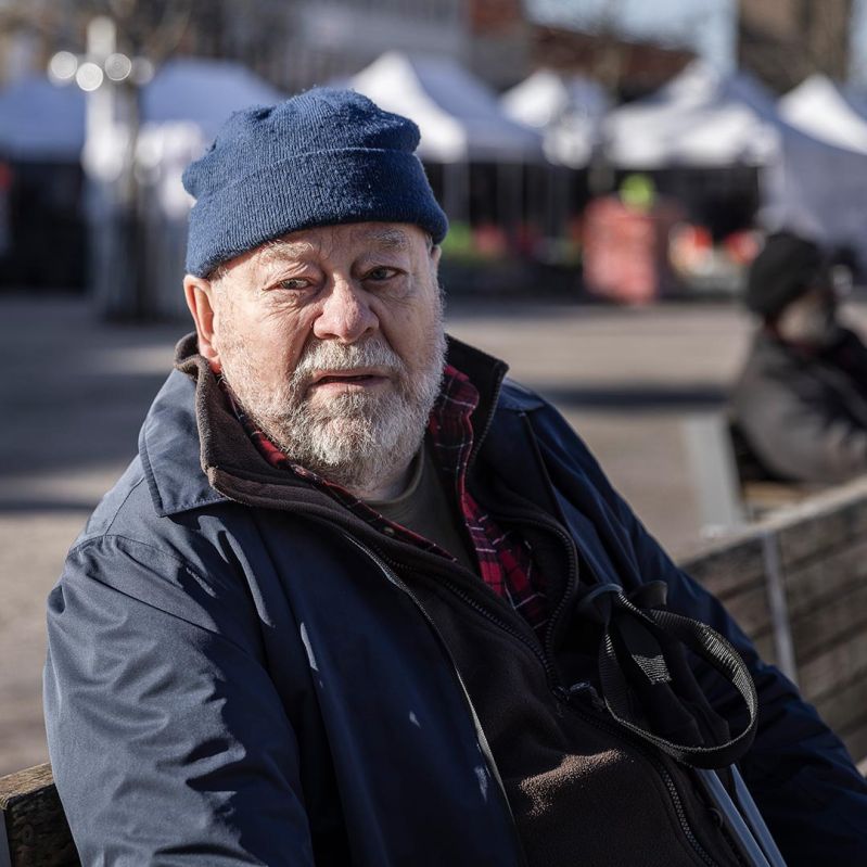 Äldre man sitter på en bänk.