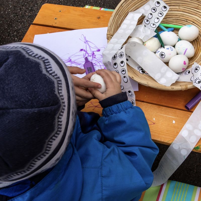 Barn påskpysslar med ägg utomhus.