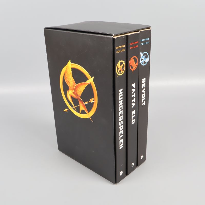Hungerspelen-trilogin i svart box, tre böcker med färgstarka motiv