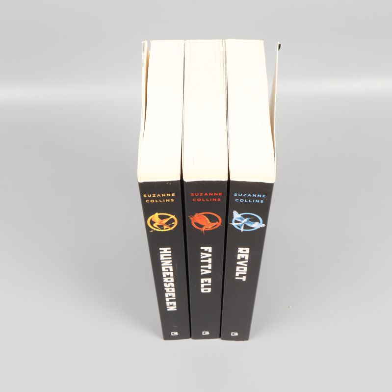 Hungerspelen-trilogin uppifrån, visar bokryggar