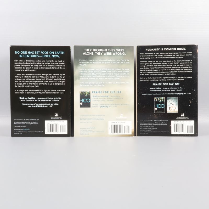 Baksidan på de tre böckerna i The 100-boxen med beskrivningar och streckkoder