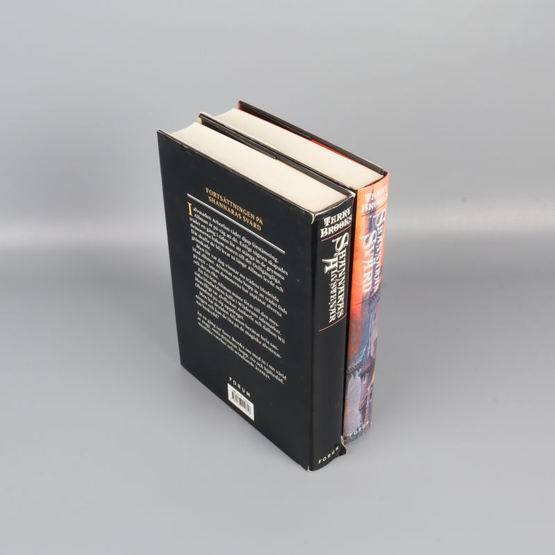 Båda böckerna stående, visande framsidor och baksidor samt bokryggar