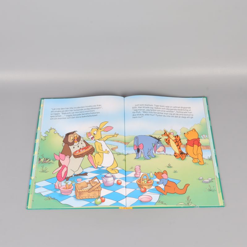 Uppslag ur Nalle Puh-bok med illustration av picknick och figurer