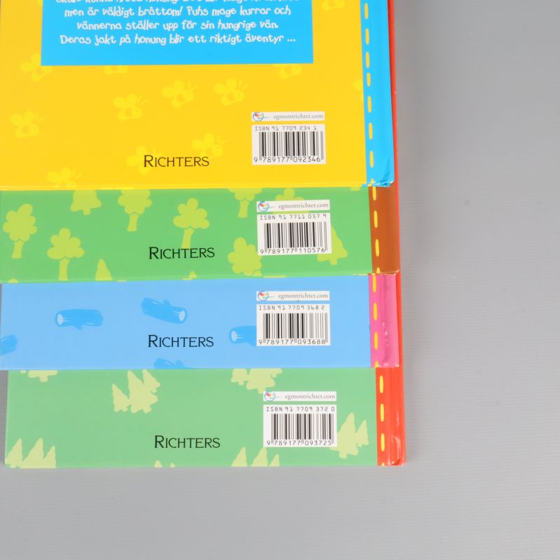 Fyra baksidor av Nalle Puh-böcker med ISBN och förlagslogga