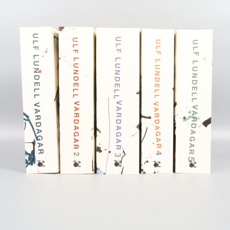 Fem böcker ur serien Vardagar av Ulf Lundell stående på rad med färgstänk på ryggarna