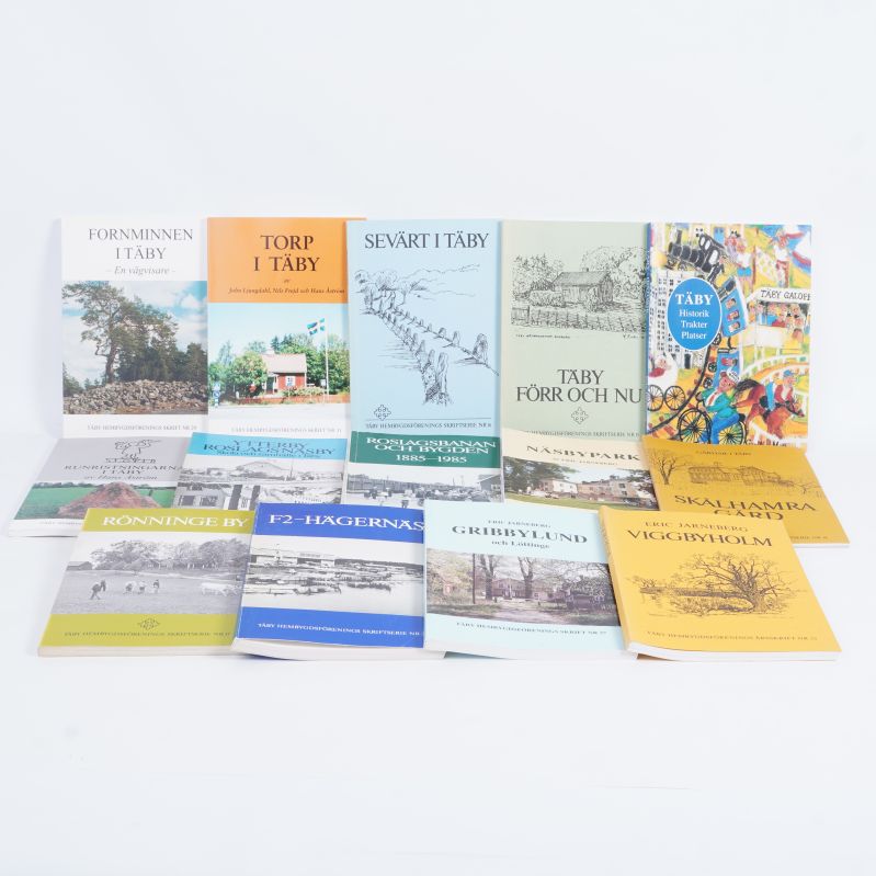 Tolv böcker om Täby uppställda sida vid sida på vitt underlag