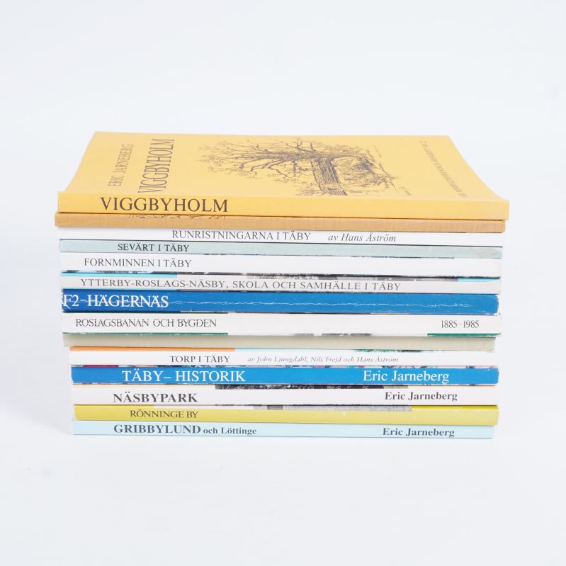 Hög med Täbyböcker i olika färger staplade med bokryggar utåt