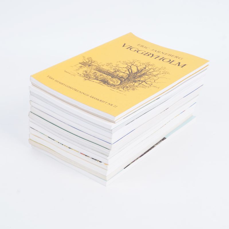 Täbyböcker liggande i hög med gul bok överst