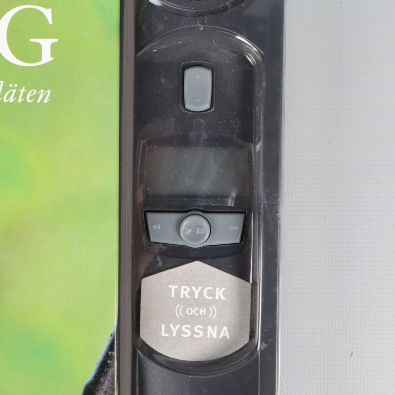 Närbild på bokens ljudmodul med knappar och texten Tryck och lyssna