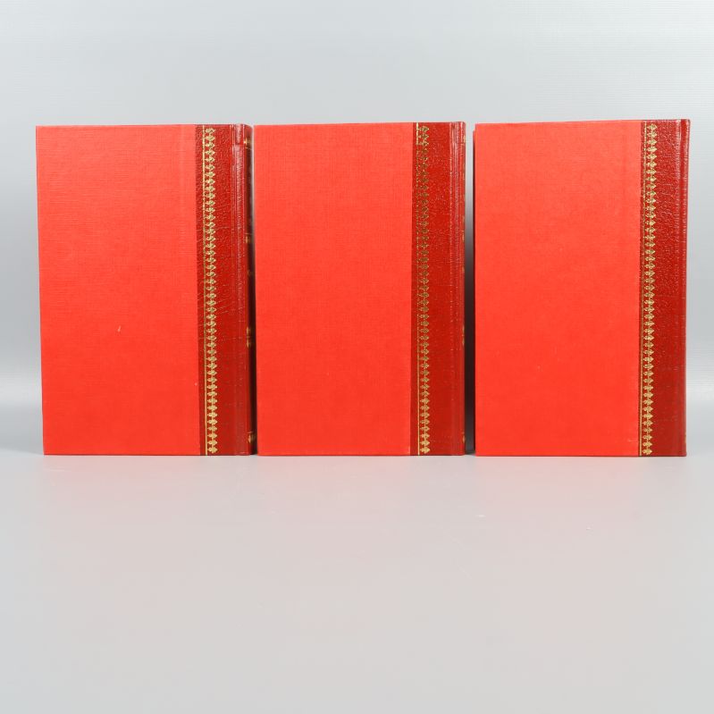 Baksida av tre röda böcker med gulddetalj