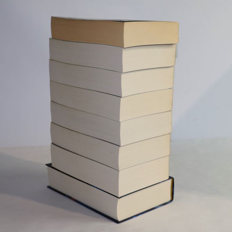 Hög med åtta böcker i De sju systrarna-serien, sedd från sidan