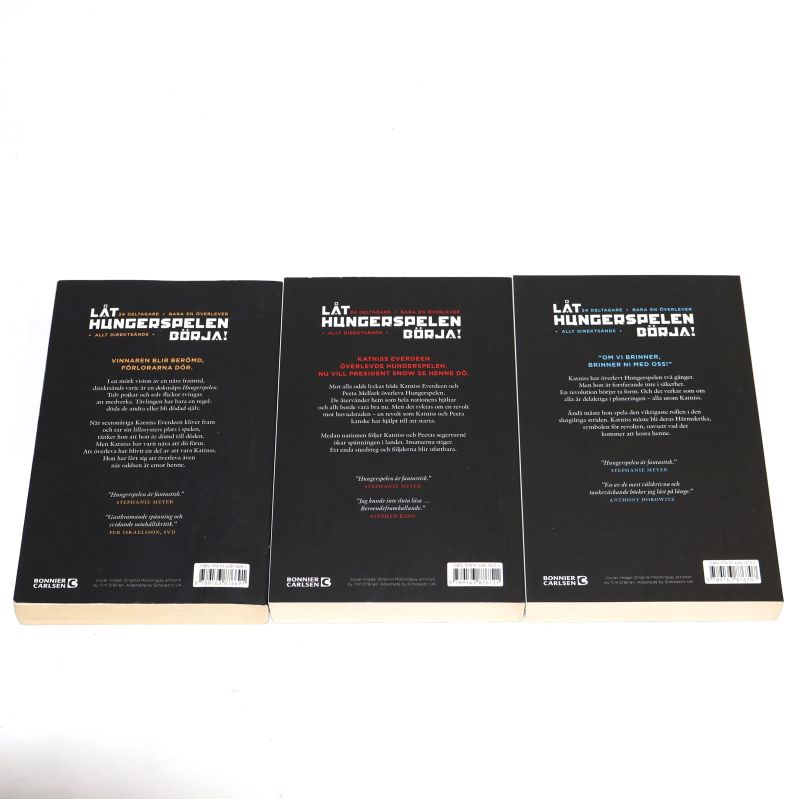 Baksidor på tre böcker ur Hungerspelen-trilogin, informationstext på varje bok och streckkod längst ner
