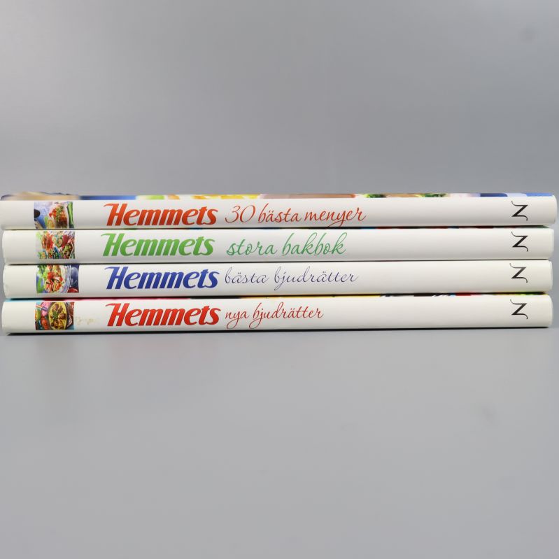 Ryggar på Hemmets kokböcker med boktitlar i olika färger staplade på rad