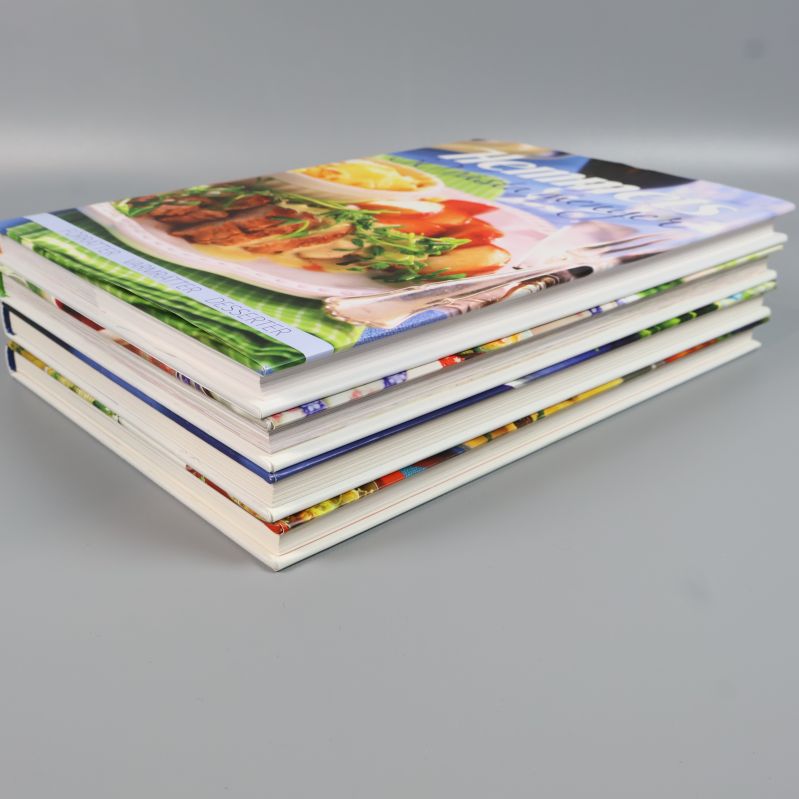 Bokhögen från sidan visar Hemmets kokböcker med olika format och omslag