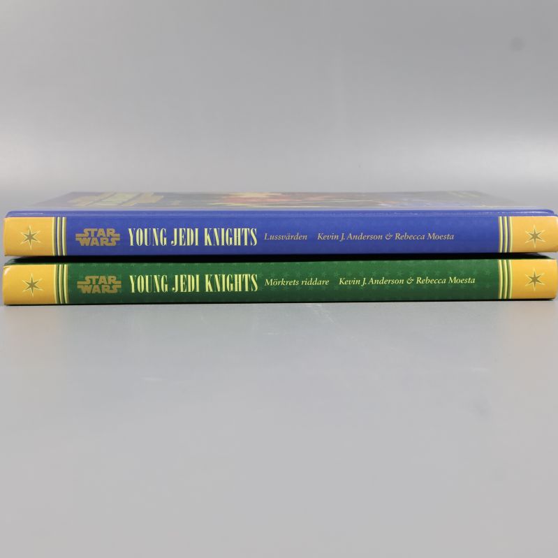 Två liggande böcker med ryggarna synliga, blå och grön färg