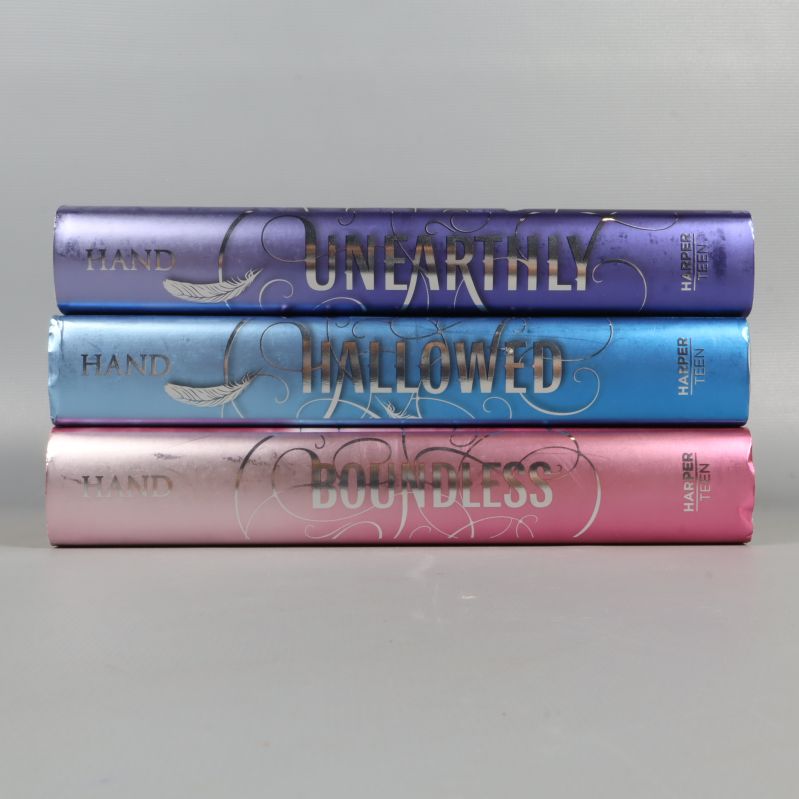 Ryggar på tre böcker med metallicfärger och titlar