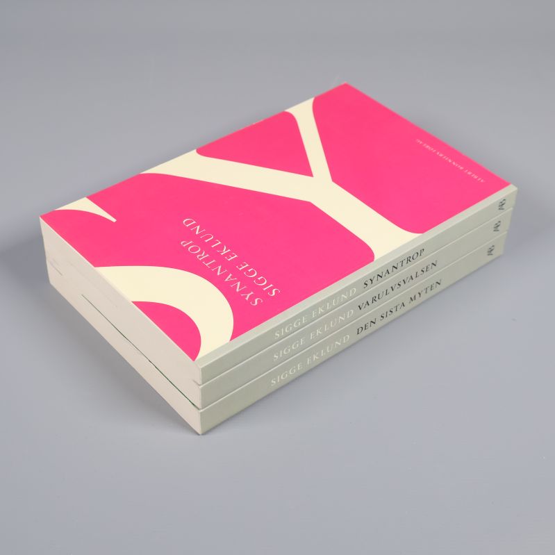 Tre böcker staplade på varandra med färgglada omslag synliga