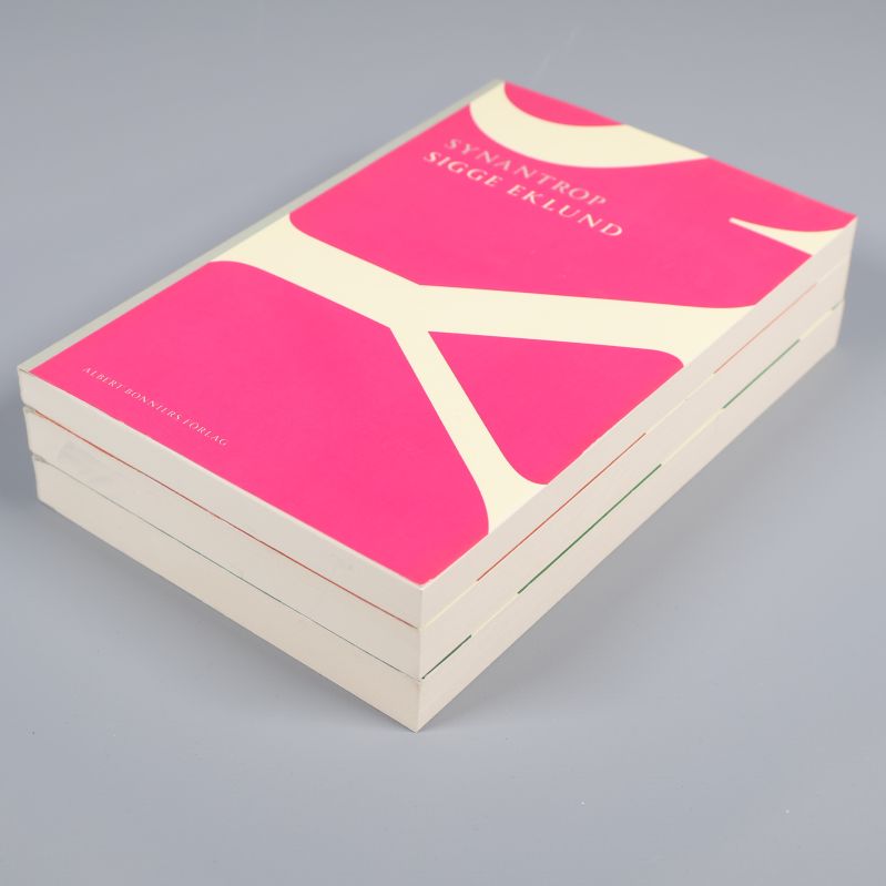 Syanthrop ovanpå två andra böcker i staplad vinkel