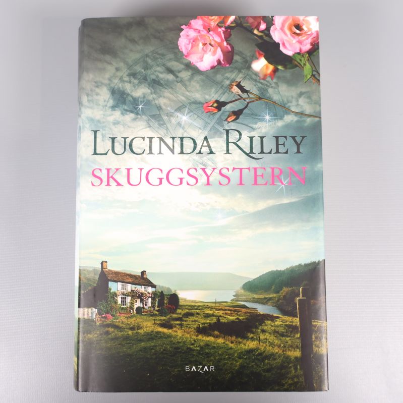 Framsidan av boken Skuggsystern av Lucinda Riley med landskapsmotiv och rosor