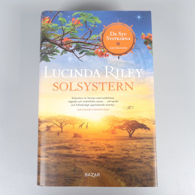 Framsidan av Solsystren av Lucinda Riley med färgstarkt landskap