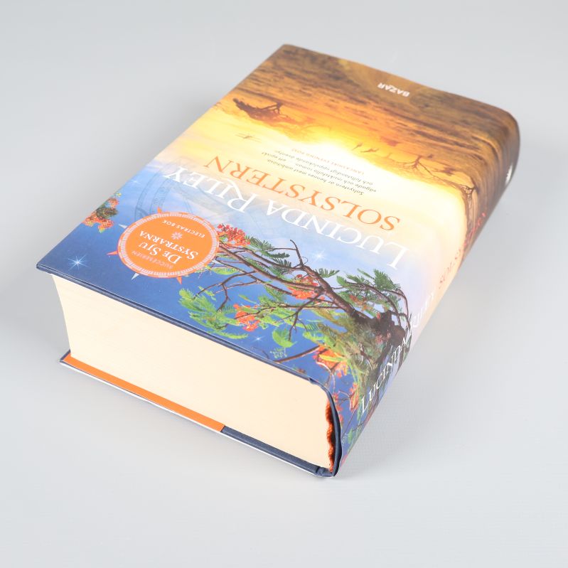 Solsystren liggande på sidan, visar bokens tjocklek