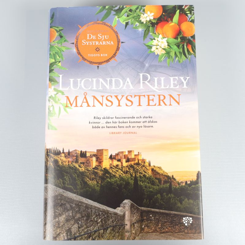 Framsida av Månsystern av Lucinda Riley, med illustration av apelsinträd och slott i solnedgång