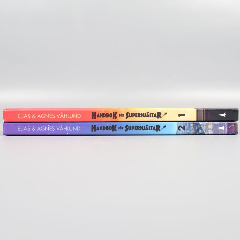 Ryggen på två böcker Handbok för superhjältar del 1 och 2 staplade på varandra