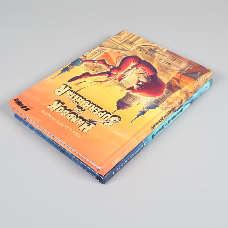 Bokpaket Handbok för superhjältar del 6-7 liggande på hög, snett uppifrån