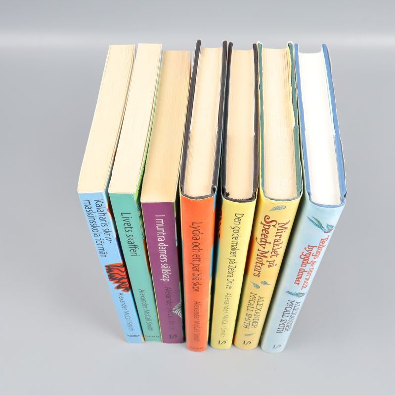 Toppvy på sju Alexander McCall Smith böcker, visar pärmar och sidor