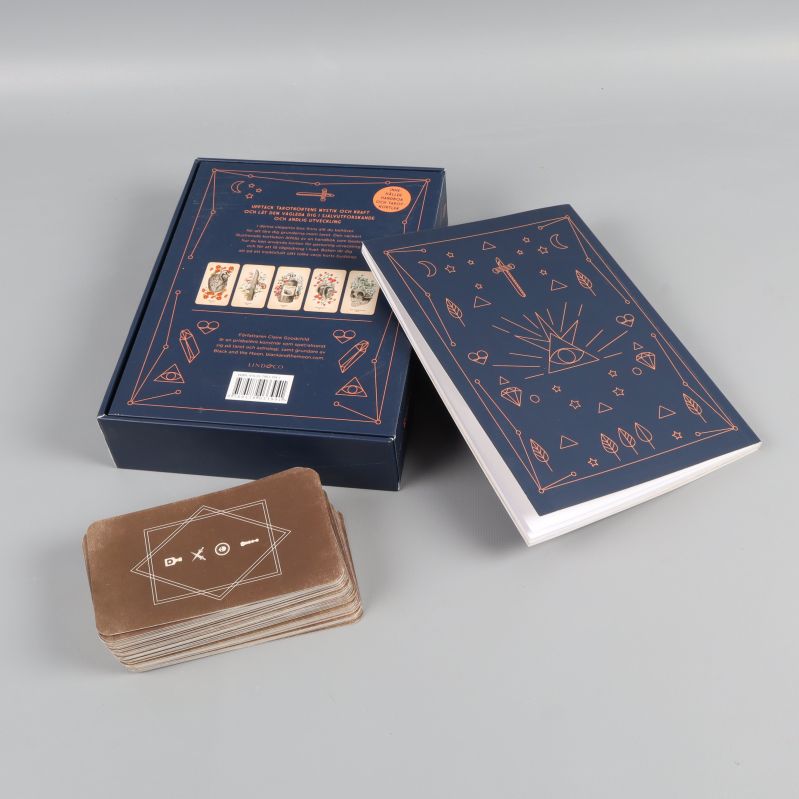 Baksidan av boxen, handbok och tarotkort staplade tillsammans