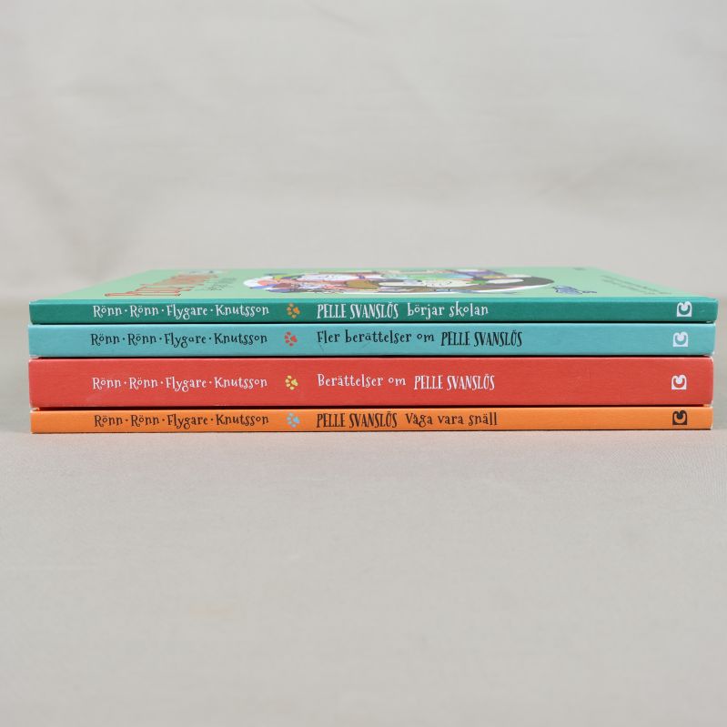 Ryggar på fyra Pelle Svanslös-böcker i olika färger staplade på varandra