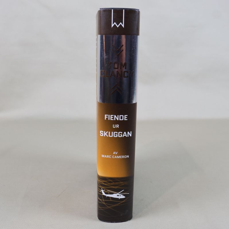 Bokrygg med Tom Clancy och Fiende ur skuggan i vitt och guld