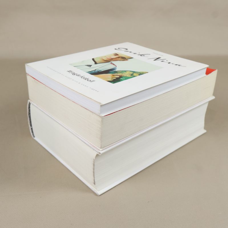 Sidovy på två staplade av Erik Niva-böcker, visar tjocklek och papperskvalitet