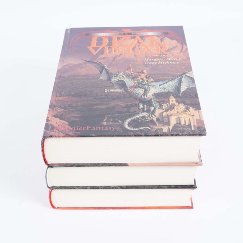 Tre staplade böcker med Drakvingar synlig överst