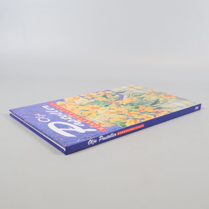 Boken Olje Pasteller diagonalt liggande med motiv på omslaget