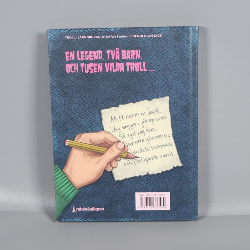 Baksida på boken Troll i järngruvan med text och illustrerad hand