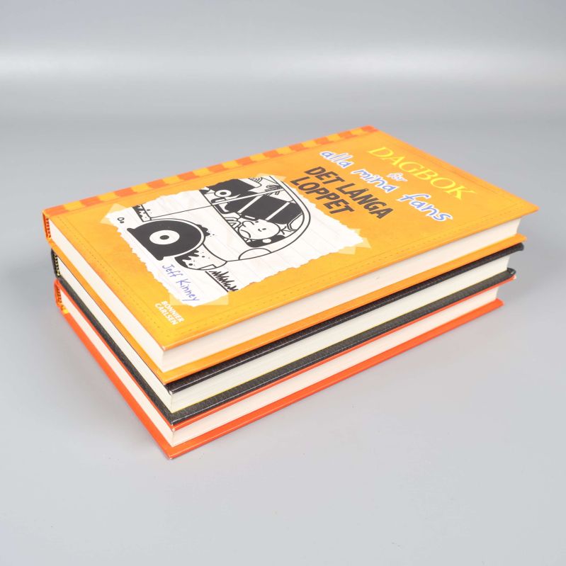 Närbild på bokstapeln med tydliga omslag och hörn i orange och svart