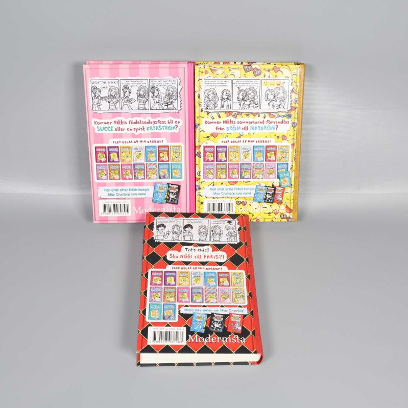 Baksidor av tre Nikkis dagbok-böcker med serierutor