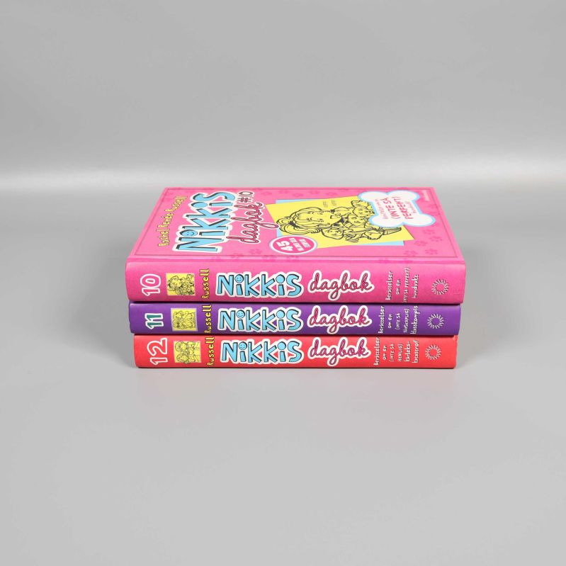 Nikkis dagbok 10-12 staplade med ryggarna mot kameran