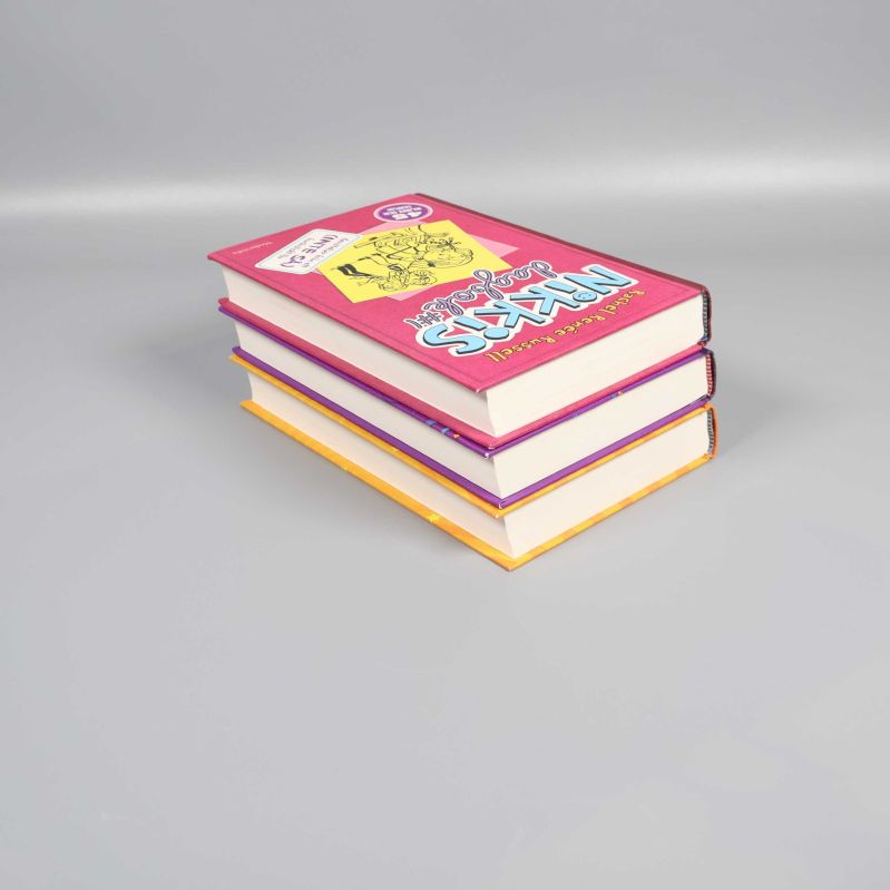 Tre böcker ur Nikkis dagbok stående på hög med vita sidor