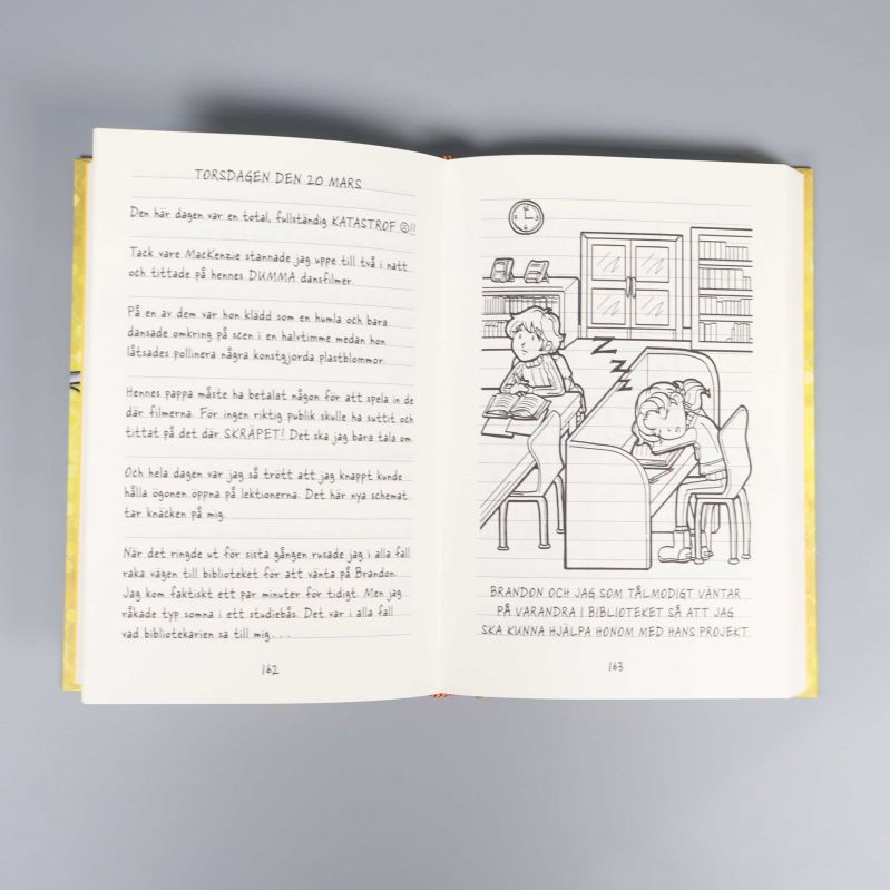 Öppet uppslag i Nikkis dagbok med dagbokstext och två figurer i bibliotek