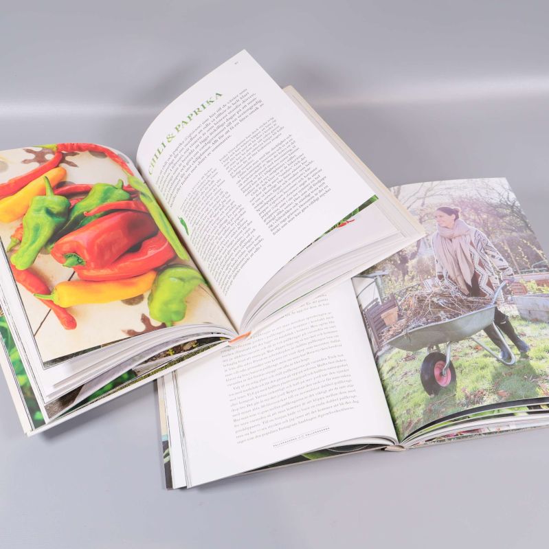 Uppslagna böcker med färgfoton av grönsaker och trädgårdsarbete