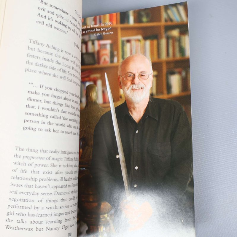 Uppslag med foto av Terry Pratchett med svärd inuti boken