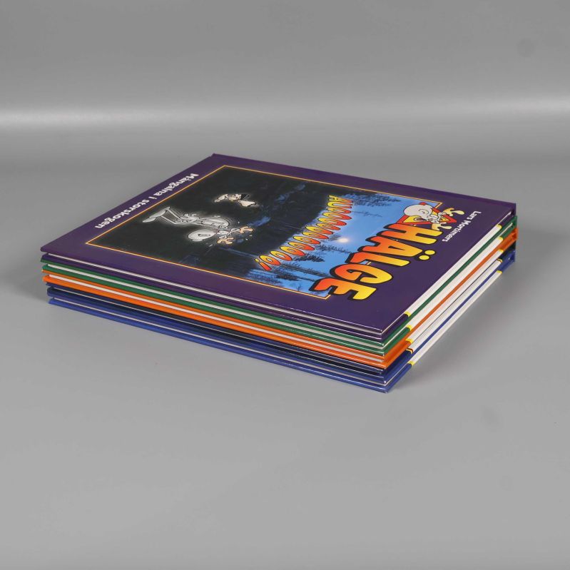 Fem staplade Hälge-album liggande på grått underlag