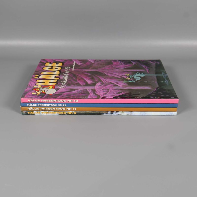 Fyra Hälge presentböcker staplade med ryggarna synliga